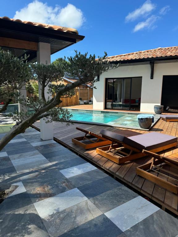 - une piscine avec chaises longues à côté d'une maison dans l'établissement Villa Luna, à La Teste-de-Buch