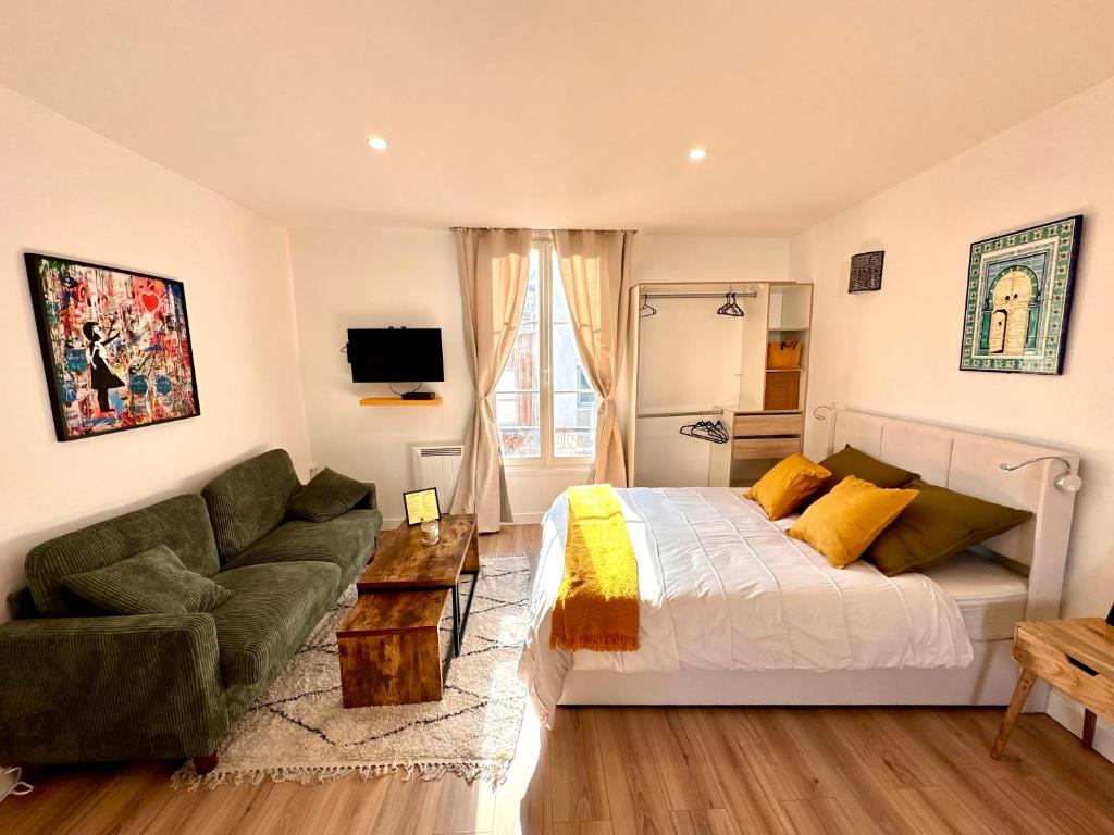 une chambre avec un lit, un canapé et une télévision dans l'établissement Magnifique Studio équipé à Clichy aux portes de Paris, à Clichy