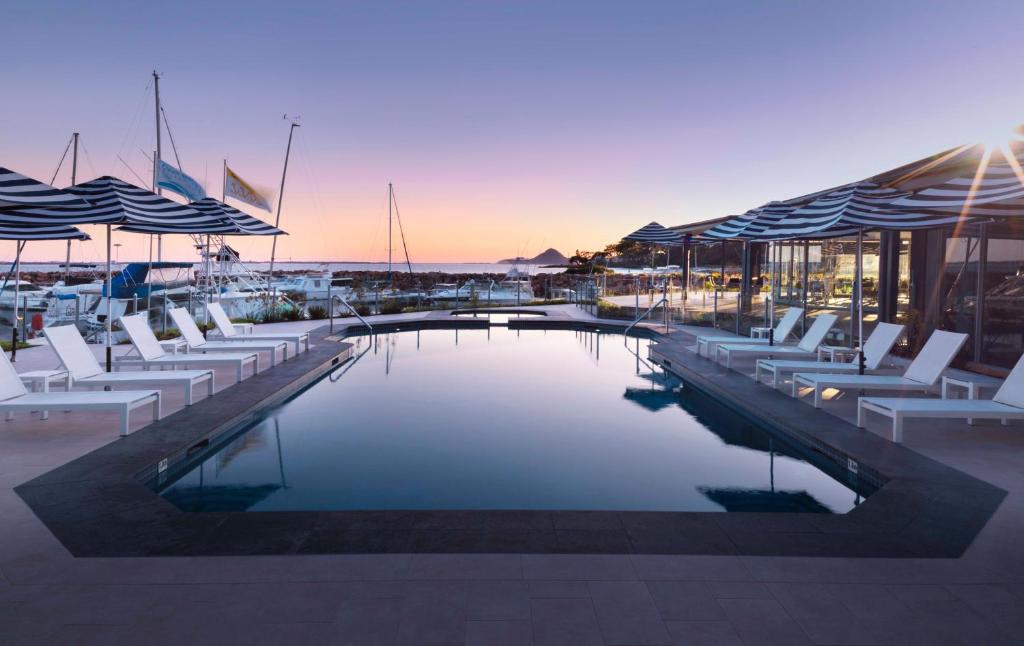 a pool with chairs and umbrellas on a building at Anchorage Port Stephens in Nelson Bay