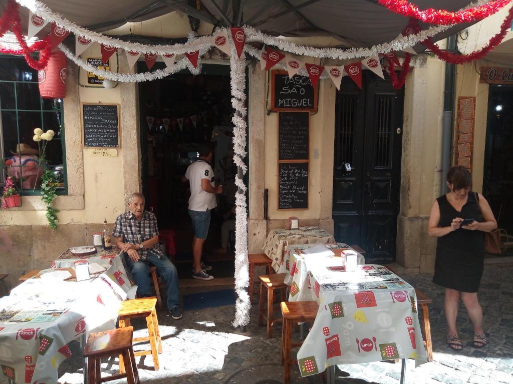 a man and a woman standing in front of a restaurant with tables at Sweet Alfama, Apartment 2 in Lisbon