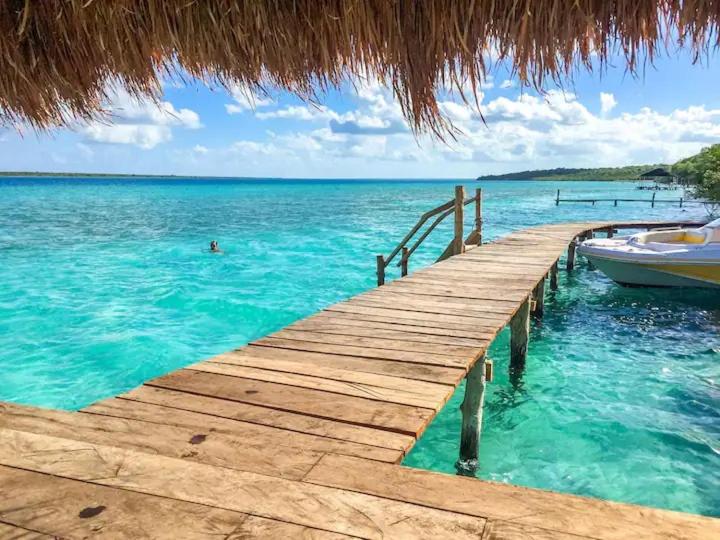 a wooden dock with a boat in the water at Casa Luna in Bacalar