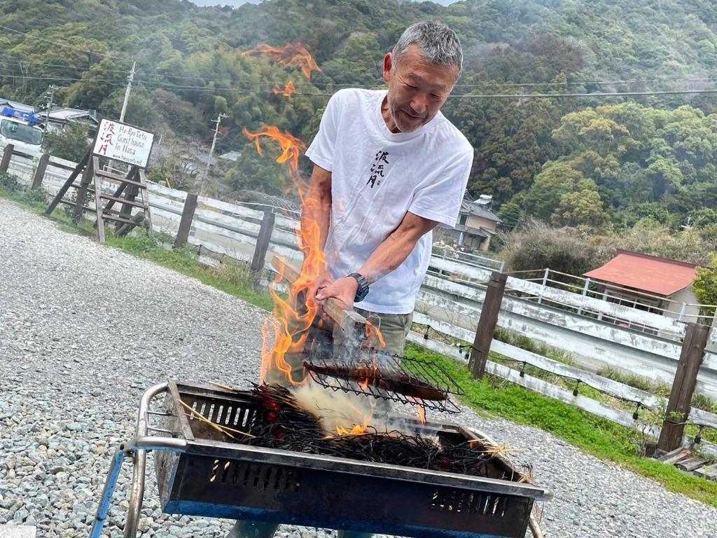 Un uomo sta cucinando cibo su una griglia di Haryugetu Guesthouse in NASA a Kaiyo