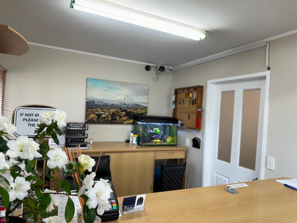 an office with a desk and a tv and flowers at Drury Motor Lodge in Drury