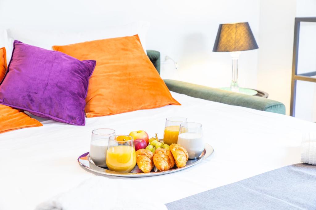 a tray of fruit and juice on a bed at Fashionable Private Flat 15 min Walk to the Olympic Village in Milan