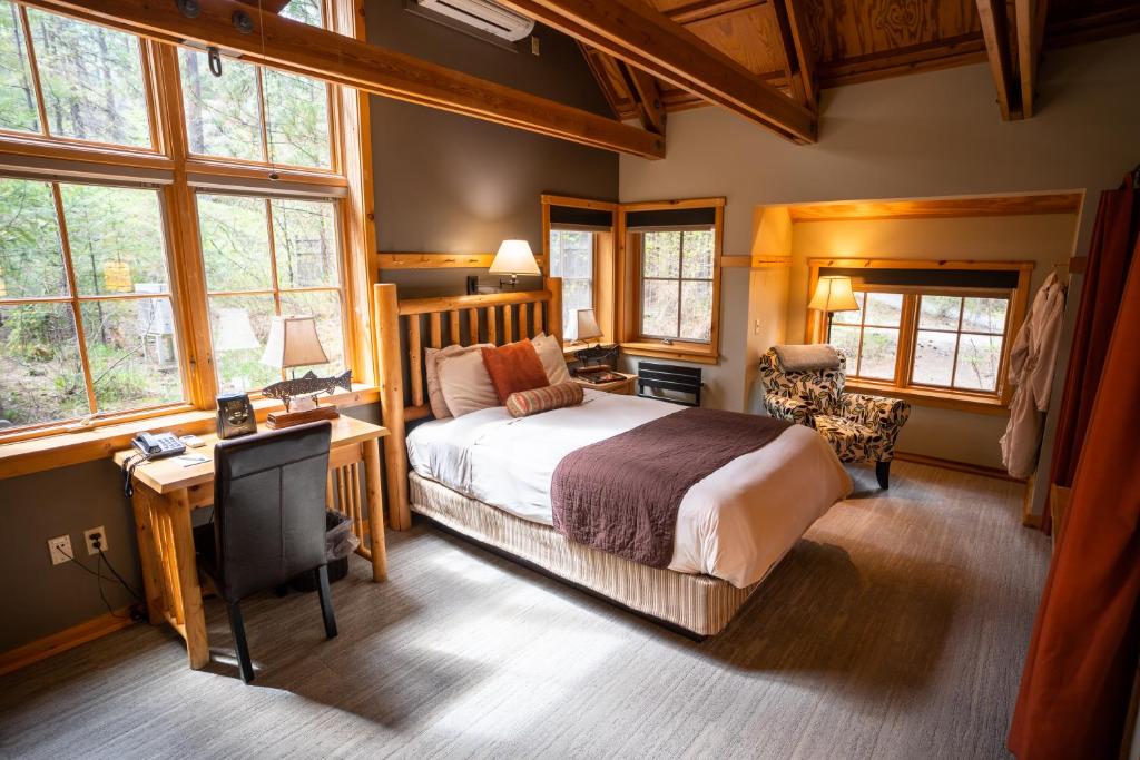 a bedroom with a bed and a desk and windows at Sleeping Lady Mountain Resort in Leavenworth