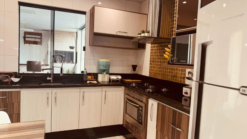 a kitchen with wooden cabinets and a refrigerator at Casa grande em bairro tranquilo in Pato Branco