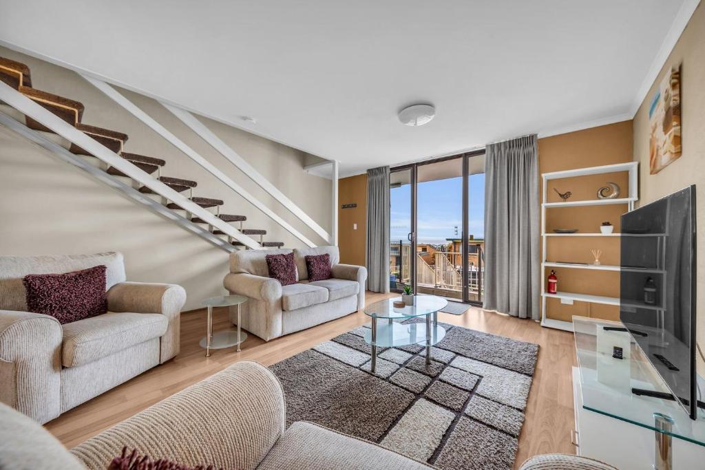 a living room with two couches and a staircase at Hydra 8 in Merimbula