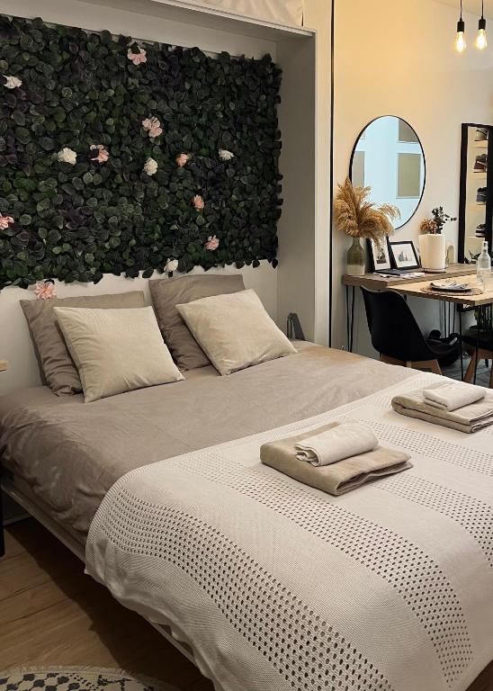 une chambre avec un grand lit avec des fleurs sur le mur dans l'établissement Charmant studio en ville, à Paris