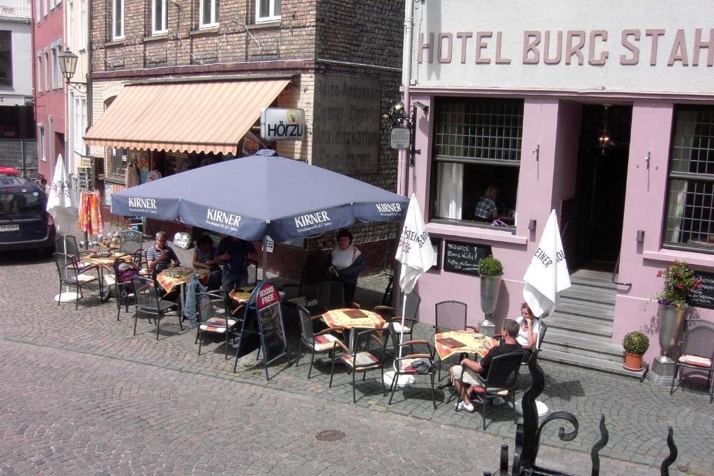 um café com mesas e cadeiras em frente a um edifício em Hotel-Café-Burg Stahleck em Bacharach