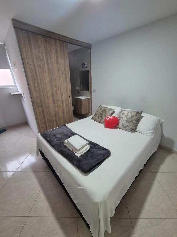 a bedroom with a large bed with a red hat on it at ApartaLoft 12, NevadaLofts Sabaneta in Sabaneta