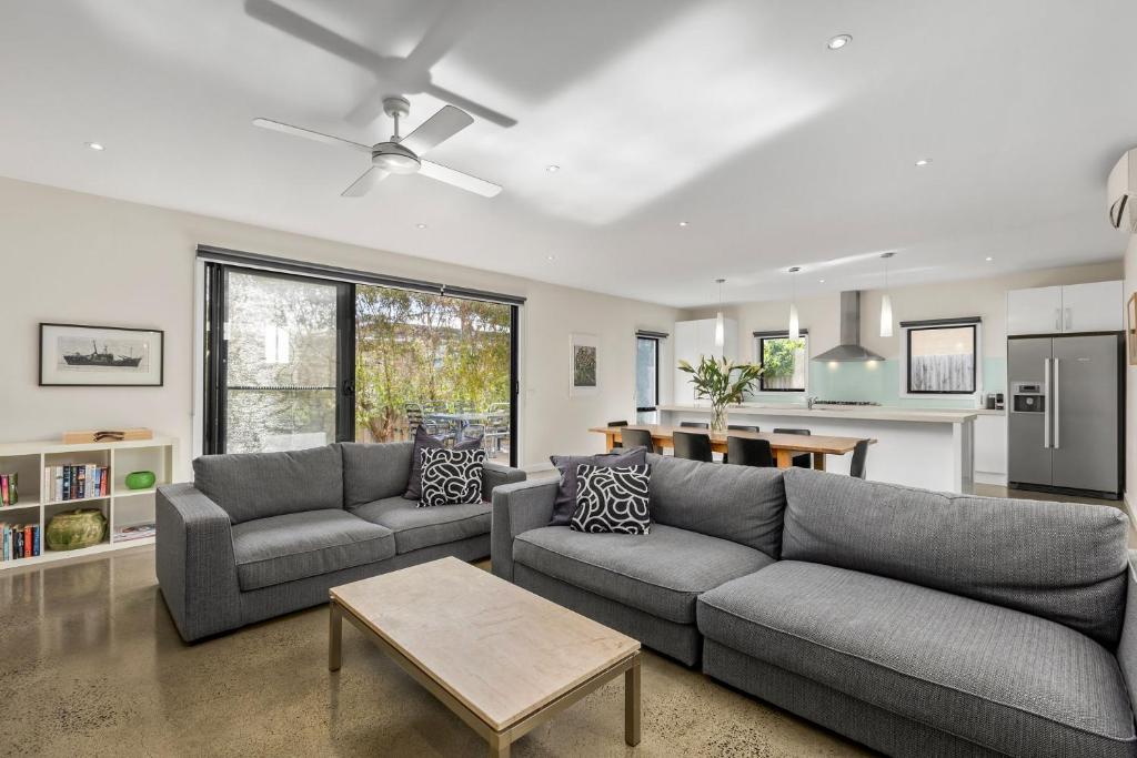 a living room with two couches and a kitchen at Seaside Getaway in Point Lonsdale