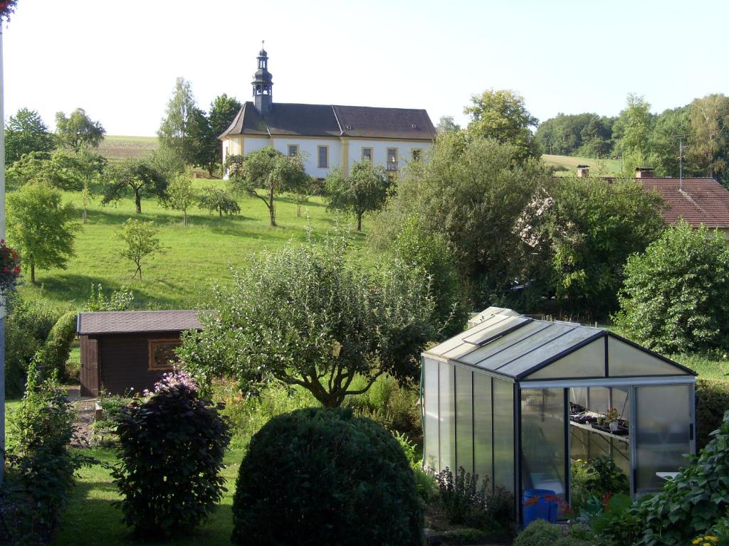 ein Gewächshaus in einem Garten mit einem Haus im Hintergrund in der Unterkunft Ferienwohnung Adelheid in Eggenbach