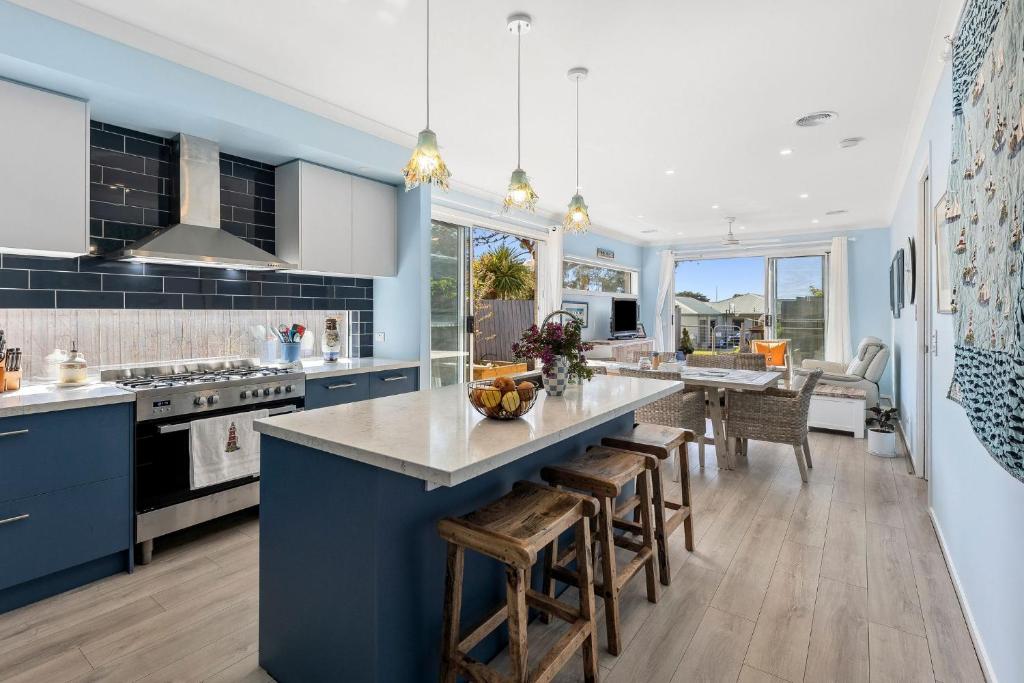 a kitchen with blue cabinets and a large island with bar stools at Serenity Nook Cottage in Point Lonsdale