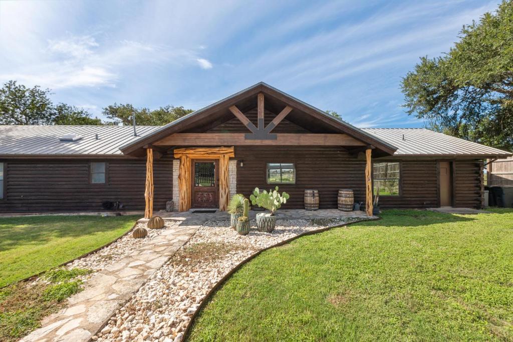 a log cabin with a pathway leading to the front door at Guadalupe Bluff Log Cabin in Kerrville