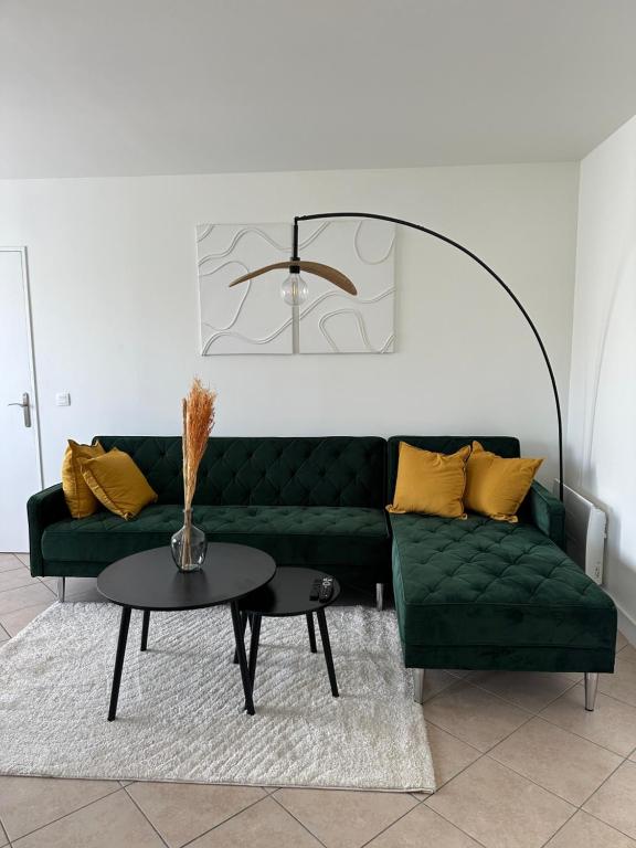 un salon avec un canapé vert et une table dans l'établissement Appartement moderne, Stade de France, Confort, Commodité, Tranquillité, à Aubervilliers