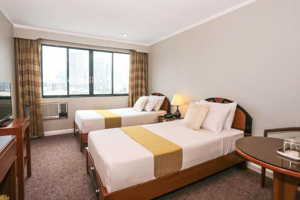 a hotel room with two beds and a table at Holiday Plaza Hotel - Cebu in Cebu City