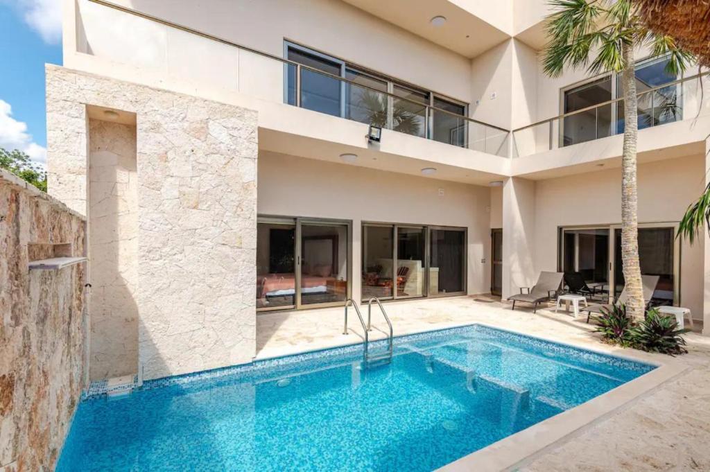 eine Villa mit einem Swimmingpool vor einem Haus in der Unterkunft Departamento 5, Tulum Country Home, con Muelle de Pesca, Club de Playa, Alberca, Cenote y Campo de Golf, Contrata Day Pass Bahia Principe in Tulum