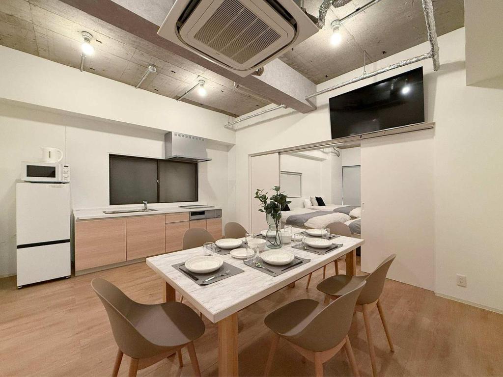 a living room with a table and chairs and a kitchen at b hotel NaouBLD - Central Hatchobori 2 Bedroom Apartment for 10 Guests in Hiroshima