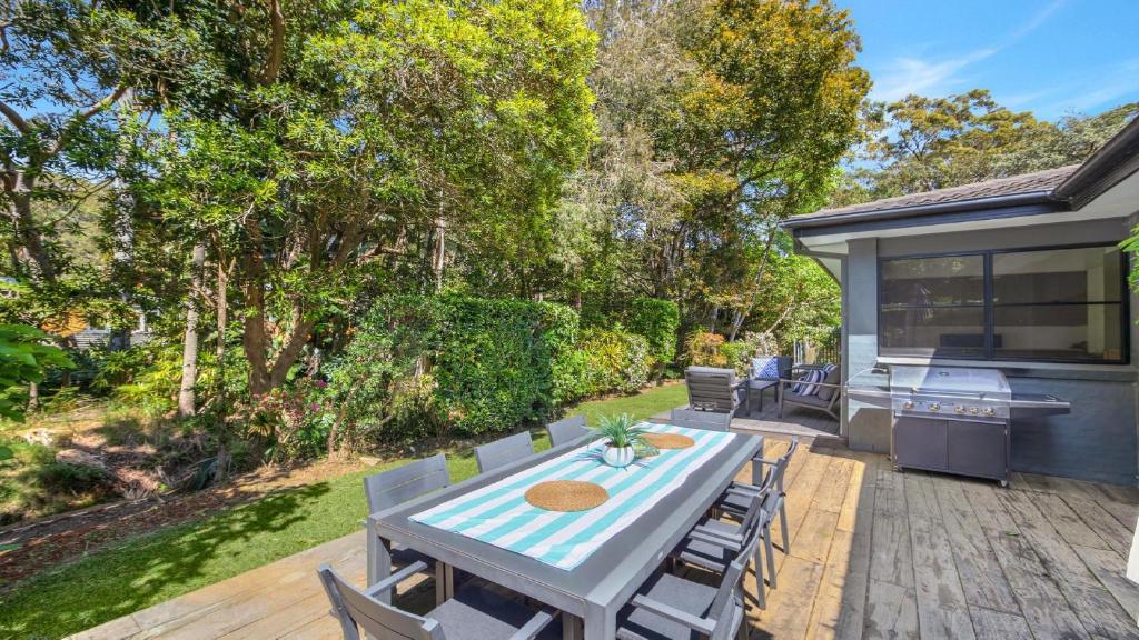 eine Terrasse mit einem Tisch, Stühlen und einem Grill in der Unterkunft Opal Oasis in Pearl Beach