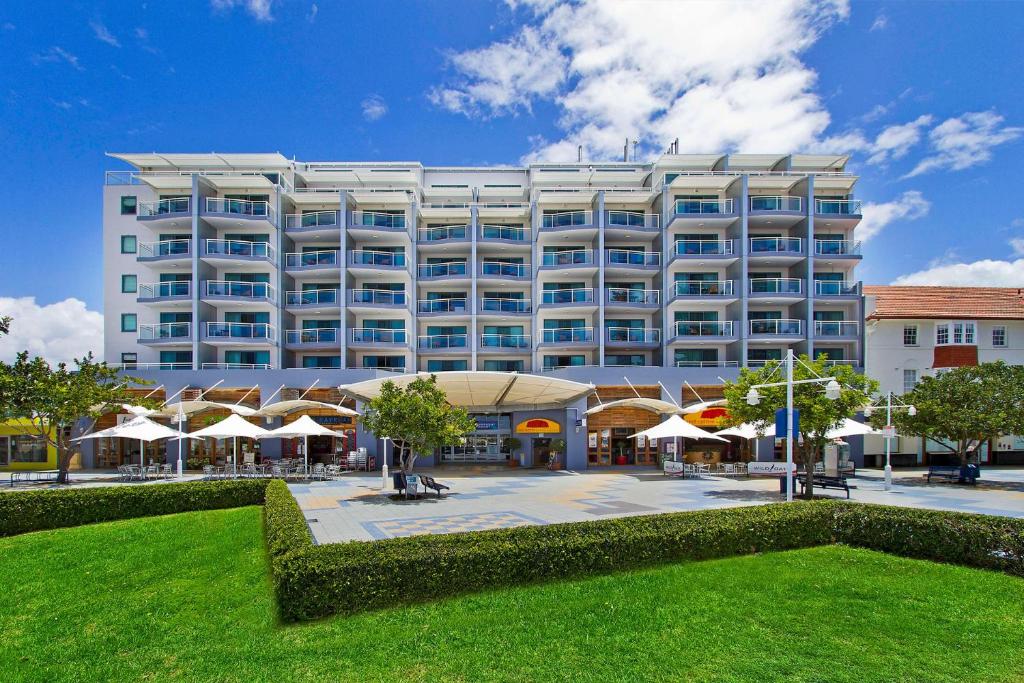 a large white building with umbrellas in front of it at The Entrance Waterfront Resort, Unit 614 in The Entrance