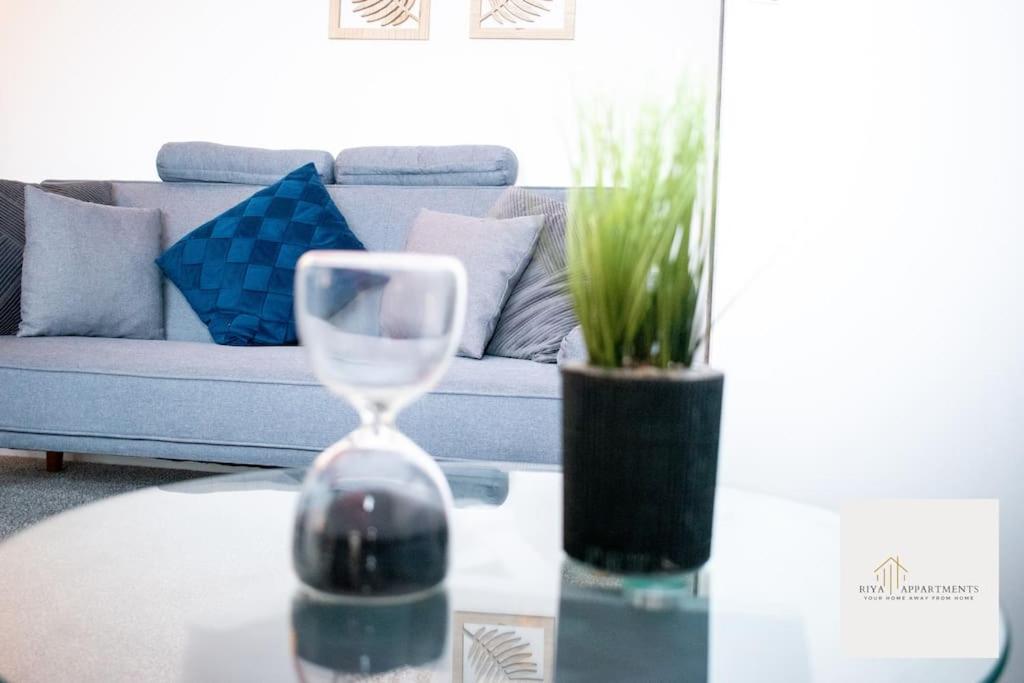 ein Wohnzimmer mit einer Couch und einem Tisch mit einer Sanduhr in der Unterkunft Riya Apartments 2 Bedroom- Wifi-Free Parking in Lemington