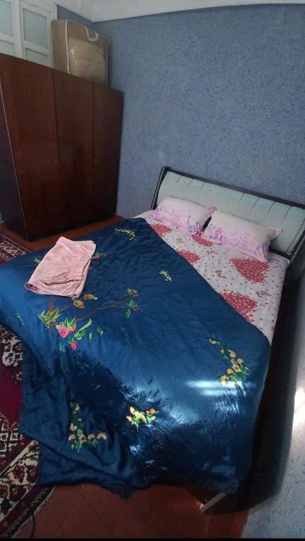 a bed with a blue blanket with flowers on it at Private Courtyard Cozy House in Tashkent