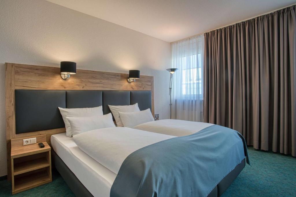 a hotel room with a large bed and a window at Centro Hotel Böblingen, Trademark Collection by Wyndham in Böblingen