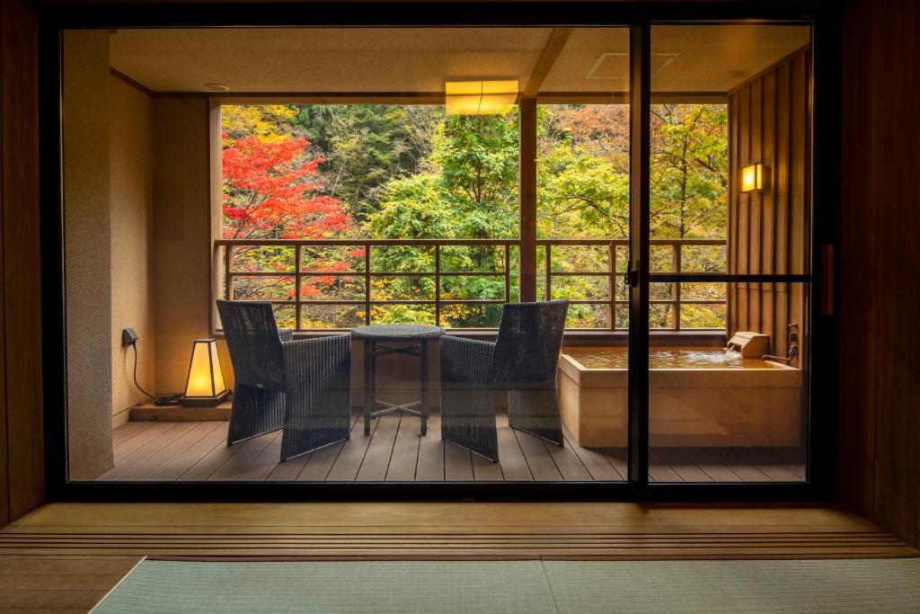 a balcony with a table and chairs and a tub at Shionoyu Onsen Rengetsu in Nasushiobara