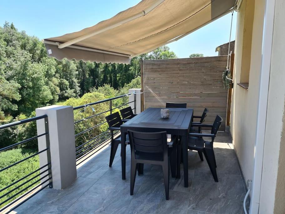 une table noire et des chaises sur un balcon dans l'établissement Appartement centre du village, à Flassans-sur-Issole