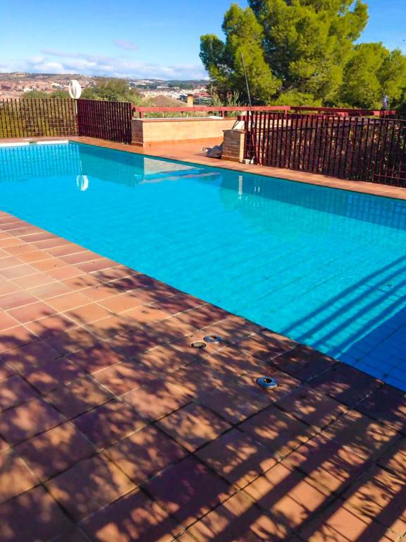 a large blue swimming pool with a fence and trees at Cigarral Valdecolomba, cerca del casco histórico in Toledo