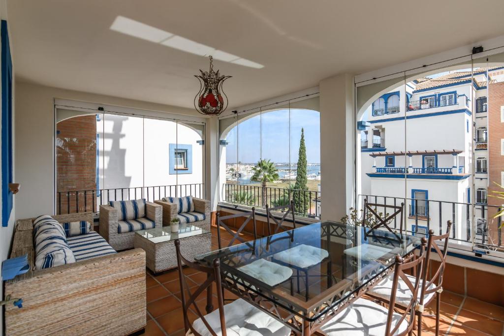 ein Wohnzimmer mit Balkon mit Glastisch in der Unterkunft Marina III PLUS by Ĥ - Marina Isla Canela PMHIII6P18 in Punta del moral