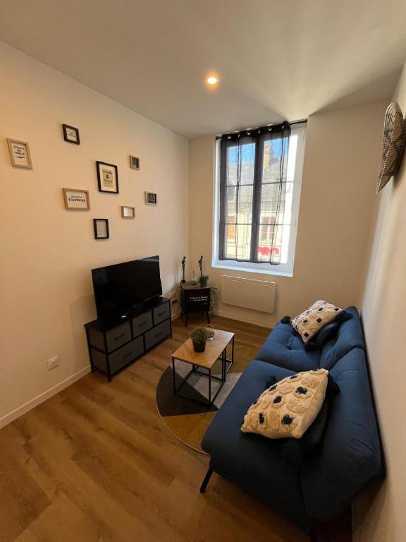 un salon avec un canapé bleu et une télévision dans l'établissement Appartement confortable, neuf en centre ville, à Cany-Barville