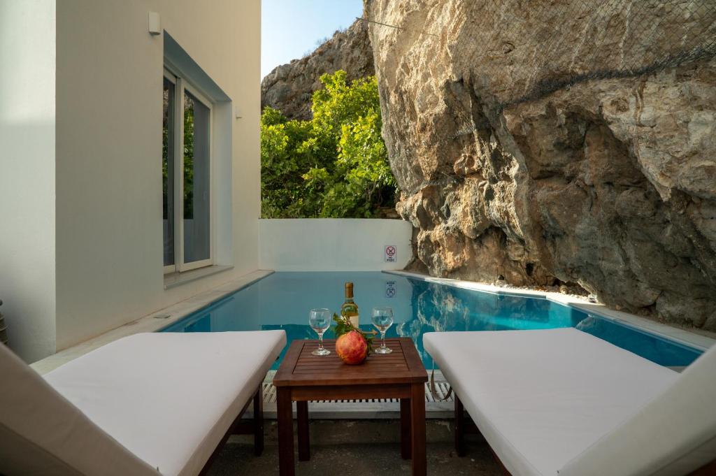a pool with two beds and a table with wine glasses at Kontemare Seascape in Koumeika