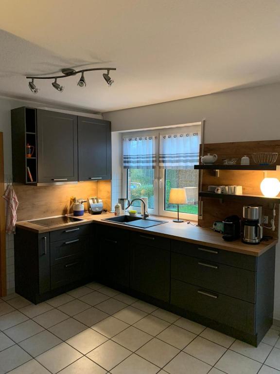 a kitchen with black cabinets and a sink and a window at Haus Petra in Borkum