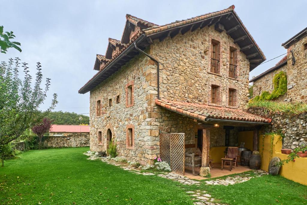 an old stone building with a grass yard at El Apartamento in Robledo de la Guzpeña