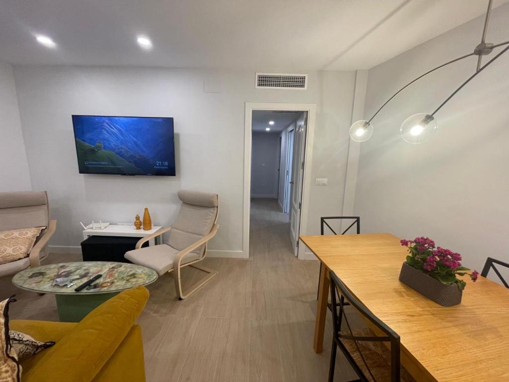 een woonkamer met een bank en een tv aan de muur bij La Casa de Lineros in Córdoba