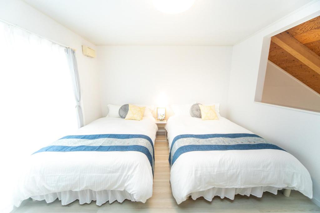 two beds in a room with white walls at Miraie Yokkaichi Hinaganishi in Nishi-hino