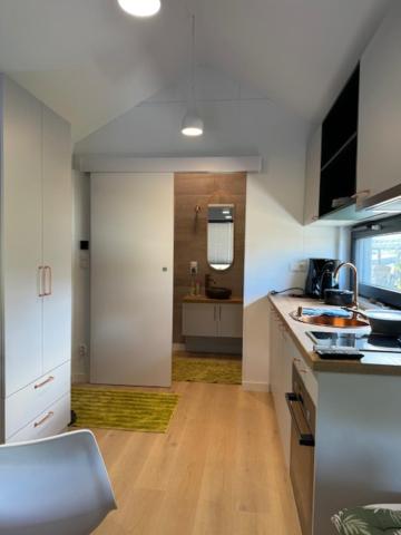 a kitchen with white cabinets and a wooden floor at Tiny Haus im Quittengarten in Distelhausen