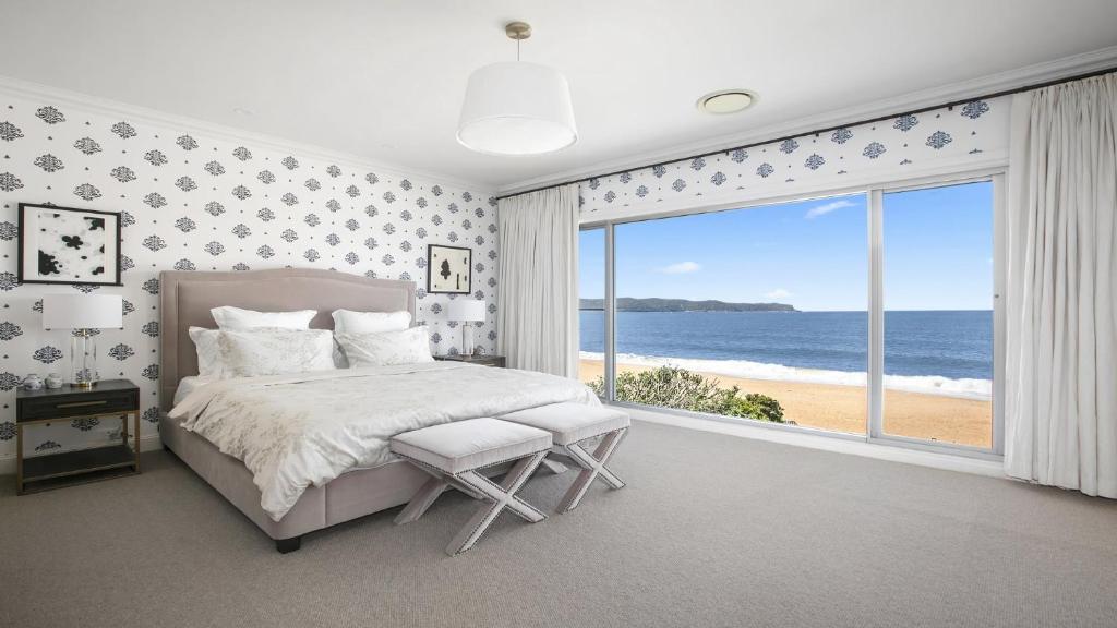 a bedroom with a bed and a view of the ocean at PIHI Beachfront , Pearl Beach, 5beds, 5 bathrooms in Pearl Beach
