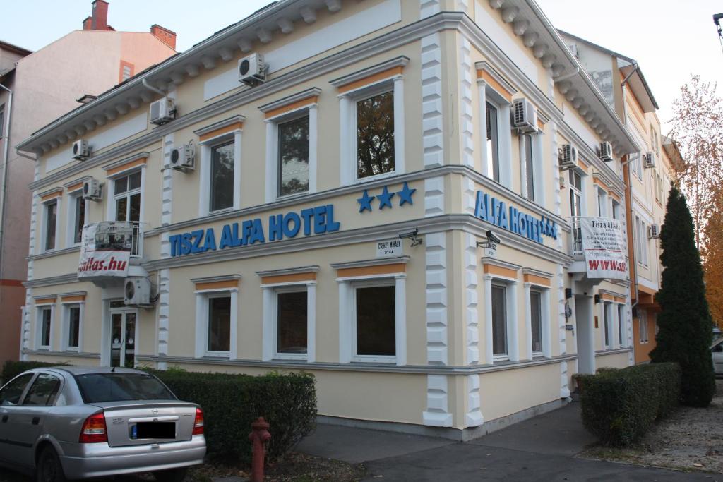 a white building with a sign on the front of it at Tisza Alfa Hotel in Szeged