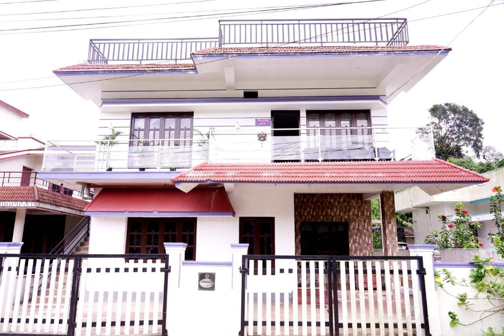 a white house with a white fence in front of it at Mulberry STAY in Madikeri