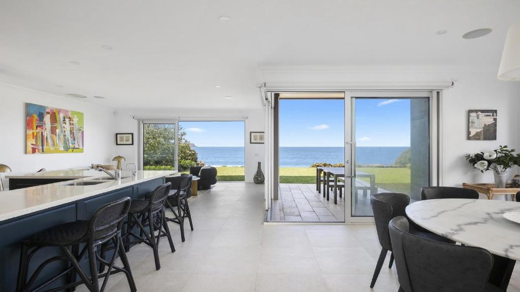 een keuken en eetkamer met uitzicht op de oceaan bij PIHI Beachfront , Pearl Beach, 5beds, 5 bathrooms in Pearl Beach