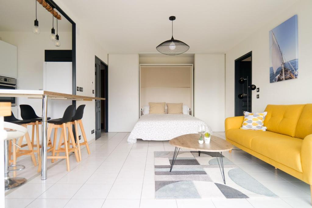 - un salon avec un canapé jaune et un lit dans l'établissement Appartement avec superbe vue sur le port de plaisance des Sables d'Olonne - 4 personnes, à Les Sables-dʼOlonne