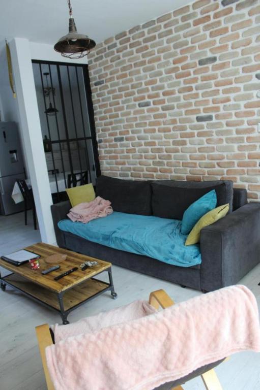 un salon avec un canapé et un mur de briques dans l'établissement T3 cosy tout confort, à Luchon