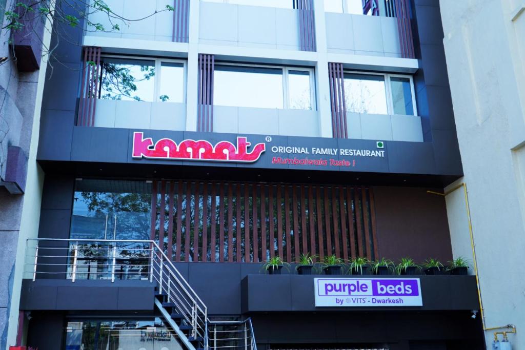 a building with a sign on the side of it at Purple Beds by VITS Dwarkesh, Surat in Salabatpura