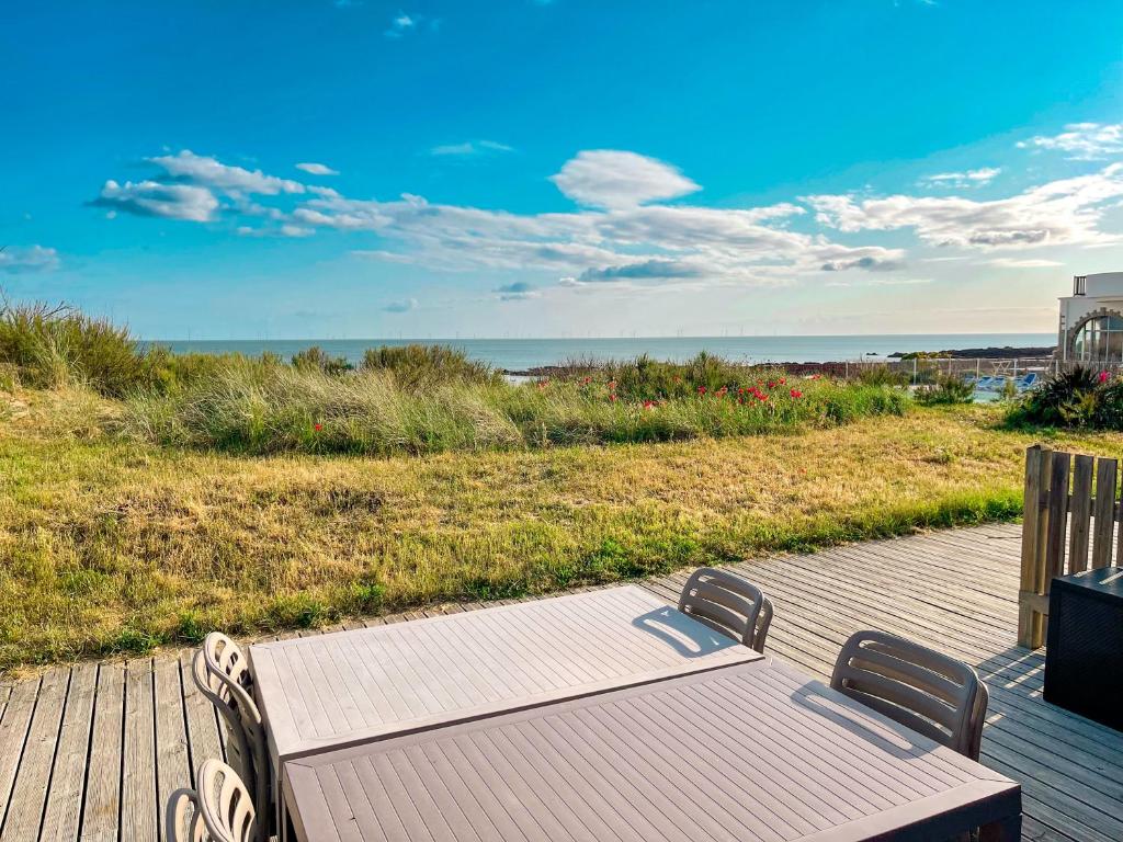 a wooden deck with a table and a view of the ocean at Valentin Beach Home ! un duplex sur la plage in Batz-sur-Mer