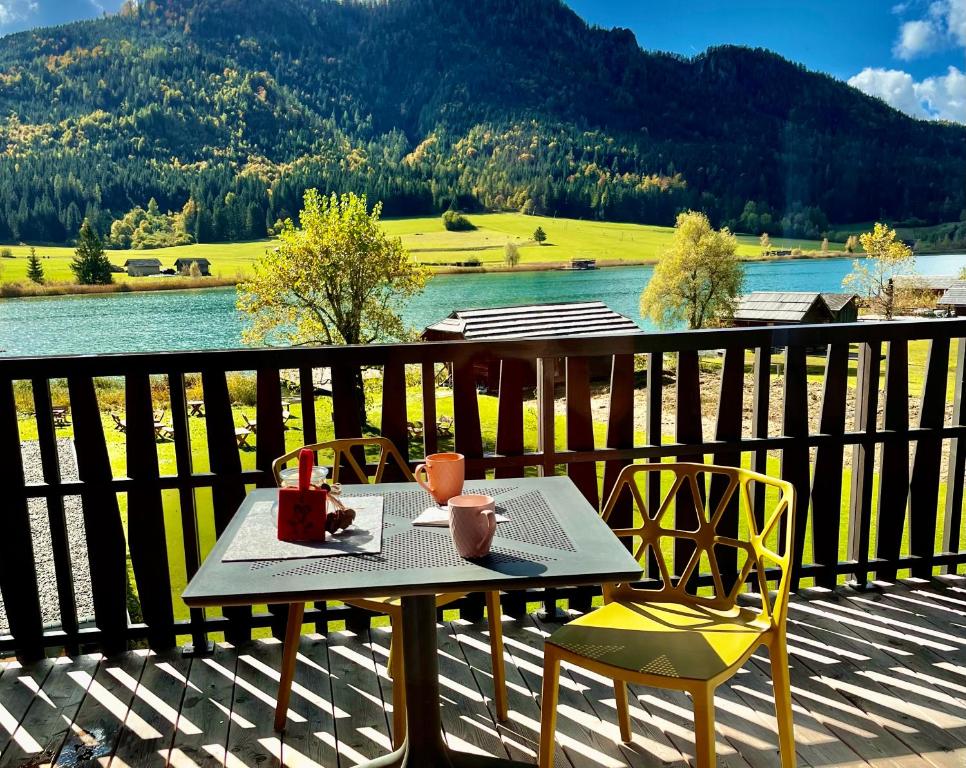 stół i krzesła na tarasie z widokiem na jezioro w obiekcie SeeHotel & SeeApartments Kärntnerhof- direkt am See! w mieście Weissensee