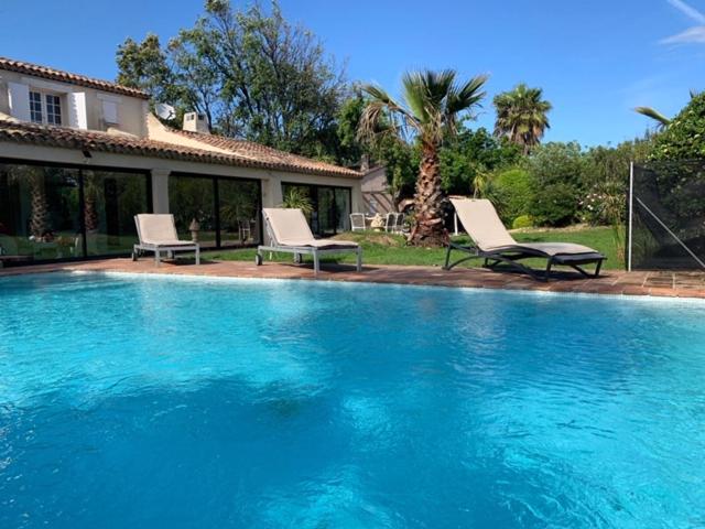 une piscine avec deux chaises et une maison dans l'établissement Villa Pampelonne-Ramatuelle, à Saint-Tropez