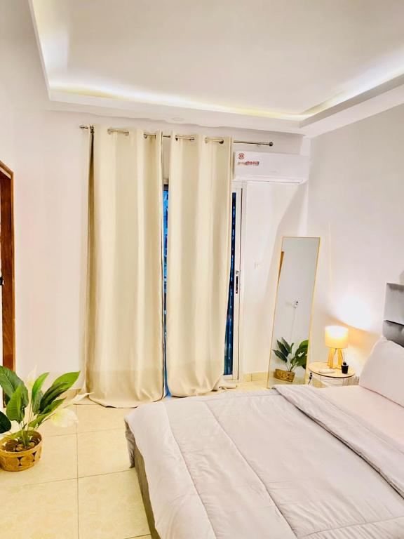 a bedroom with a bed and two windows with curtains at Résidence cosy or in Douala