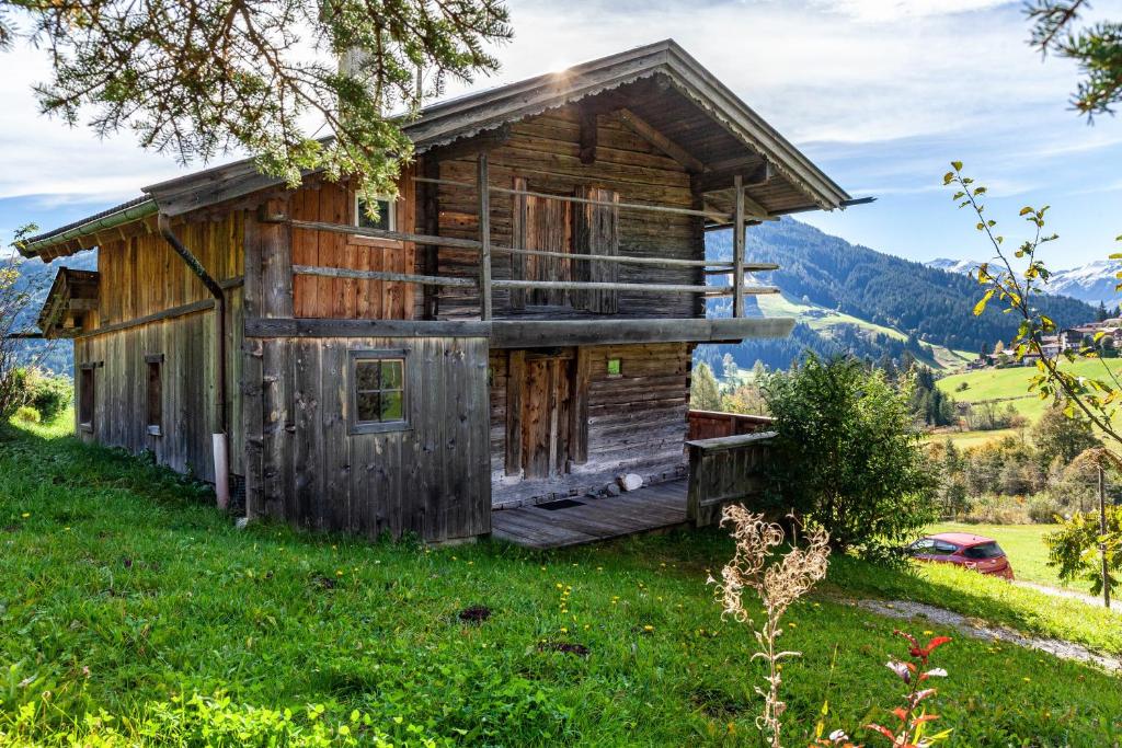 an old wooden house on a hill with mountains in the background at Kastnhäusl Wildschönau Urige Hütte in Oberau